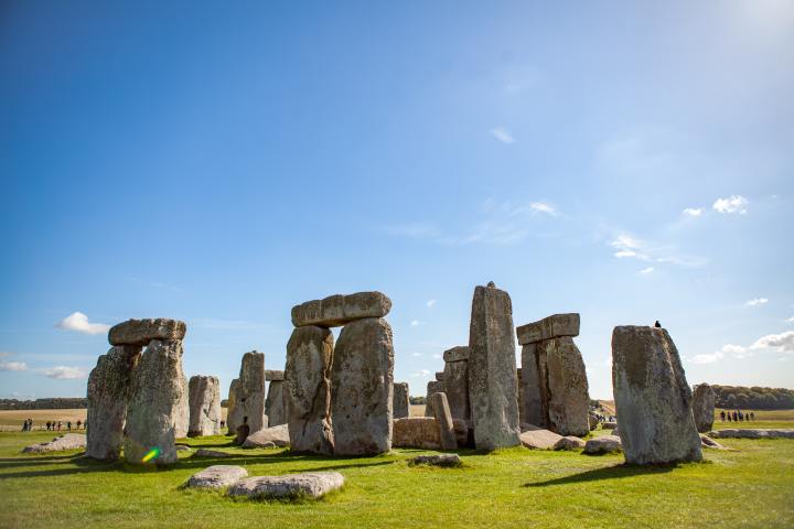 a stone castle next to a rock with Stonehenge in the background